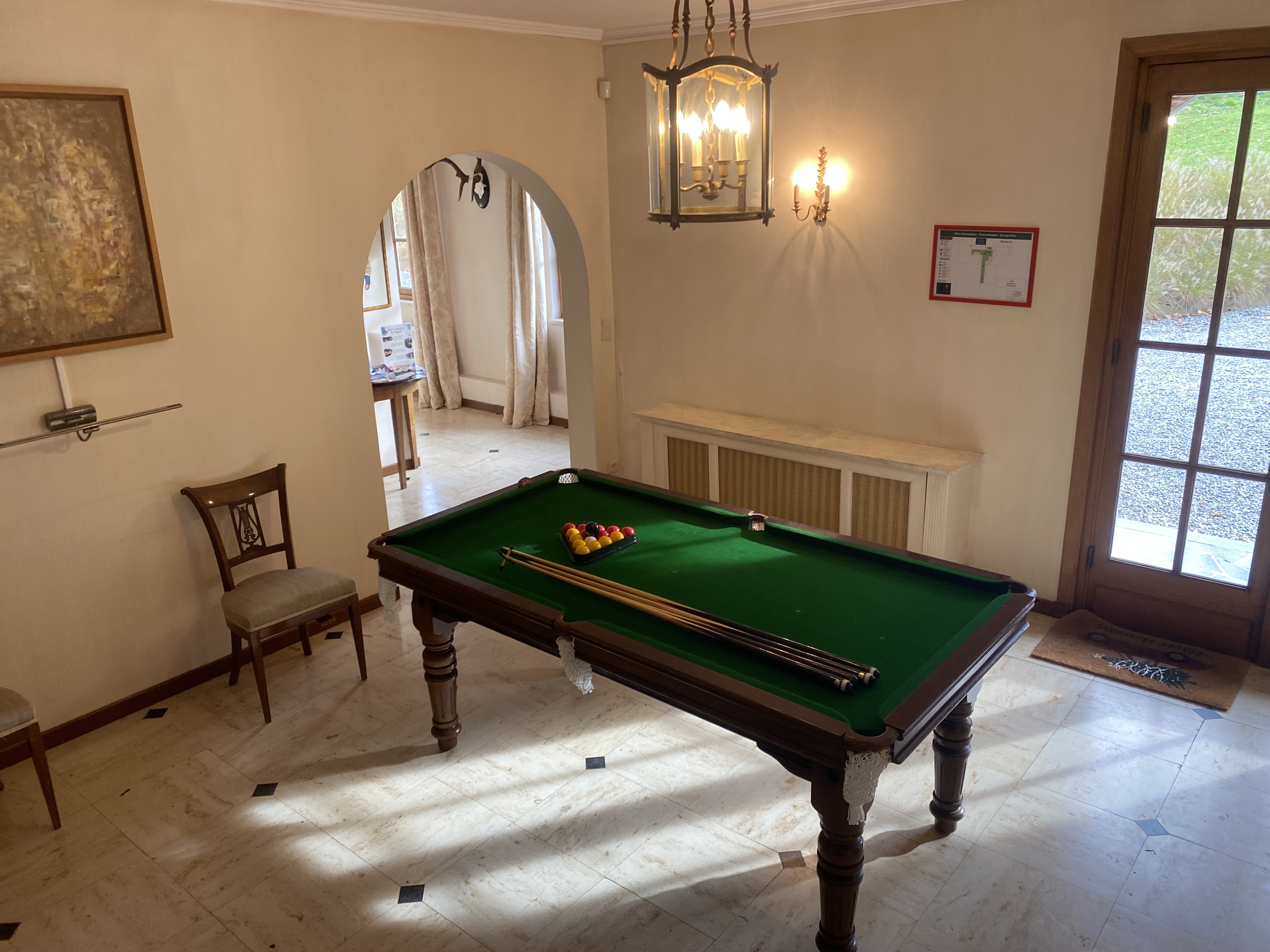 Salle de billard élégante avec luminaire classique et vue sur le jardin