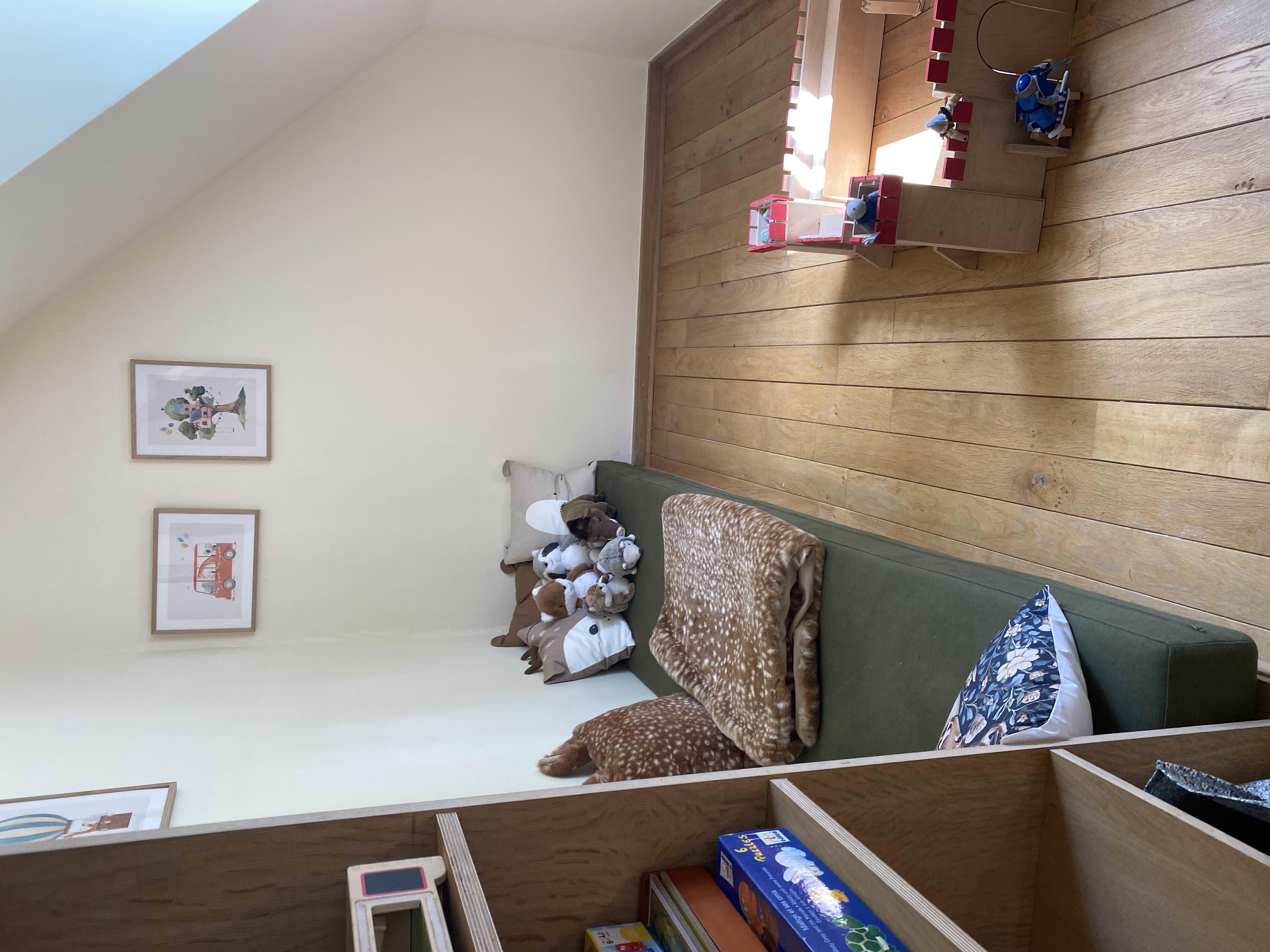 Coin jeux pour enfants avec banquette, peluches et château fort en bois
