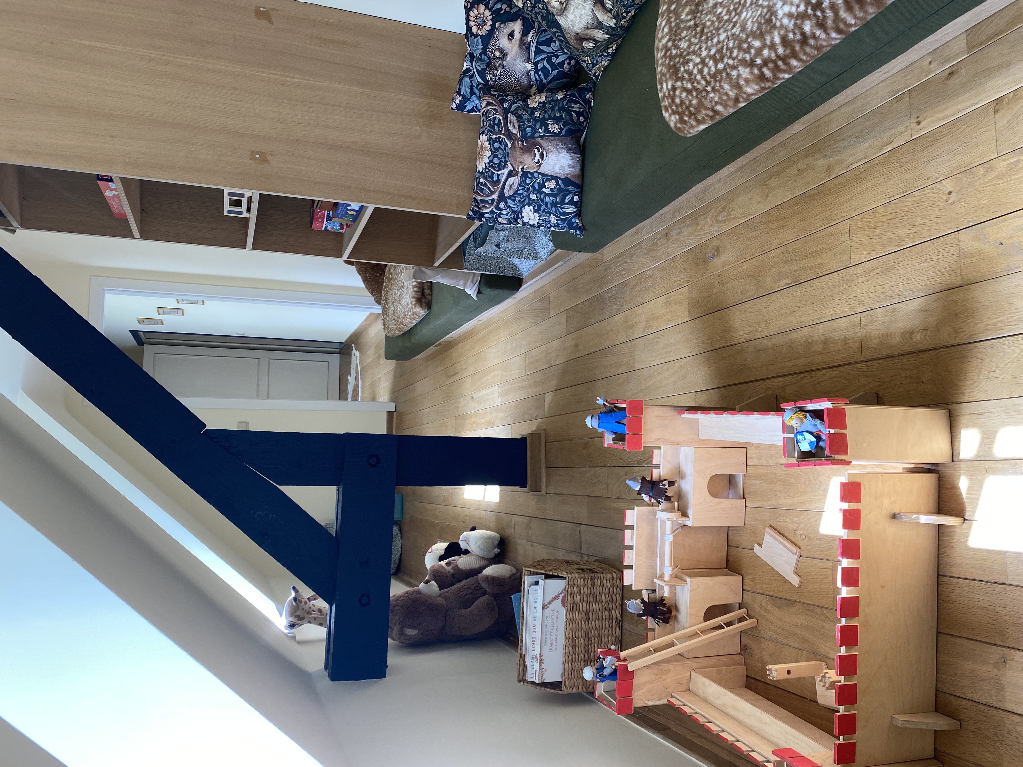 Espace de jeux pour enfants avec château en bois et coin lecture sous les combles