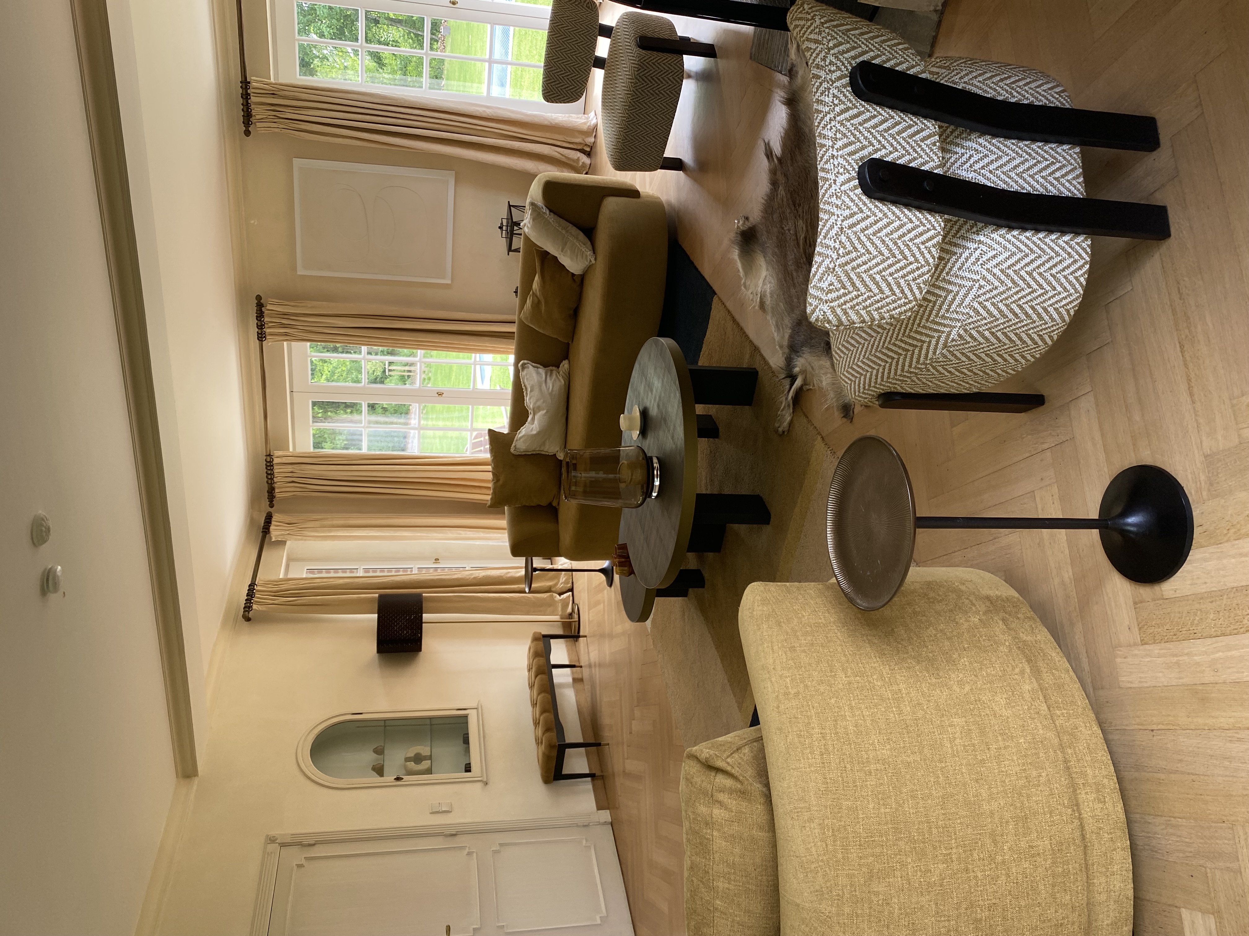 Salon lumineux avec canapé incurvé, fauteuils à chevrons et niches vitrées