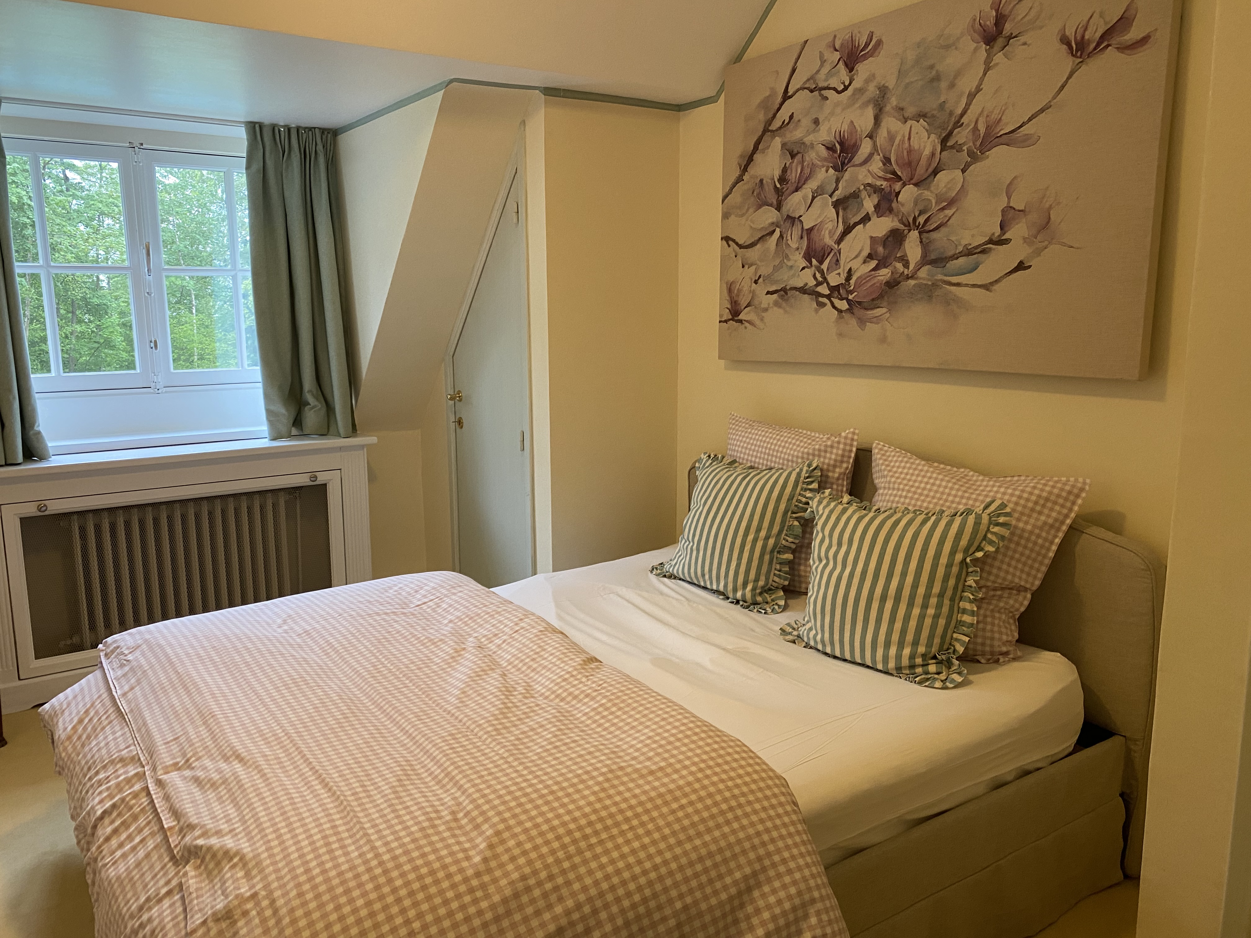 Chambre avec lit double aux motifs vichy roses et peinture de magnolias
