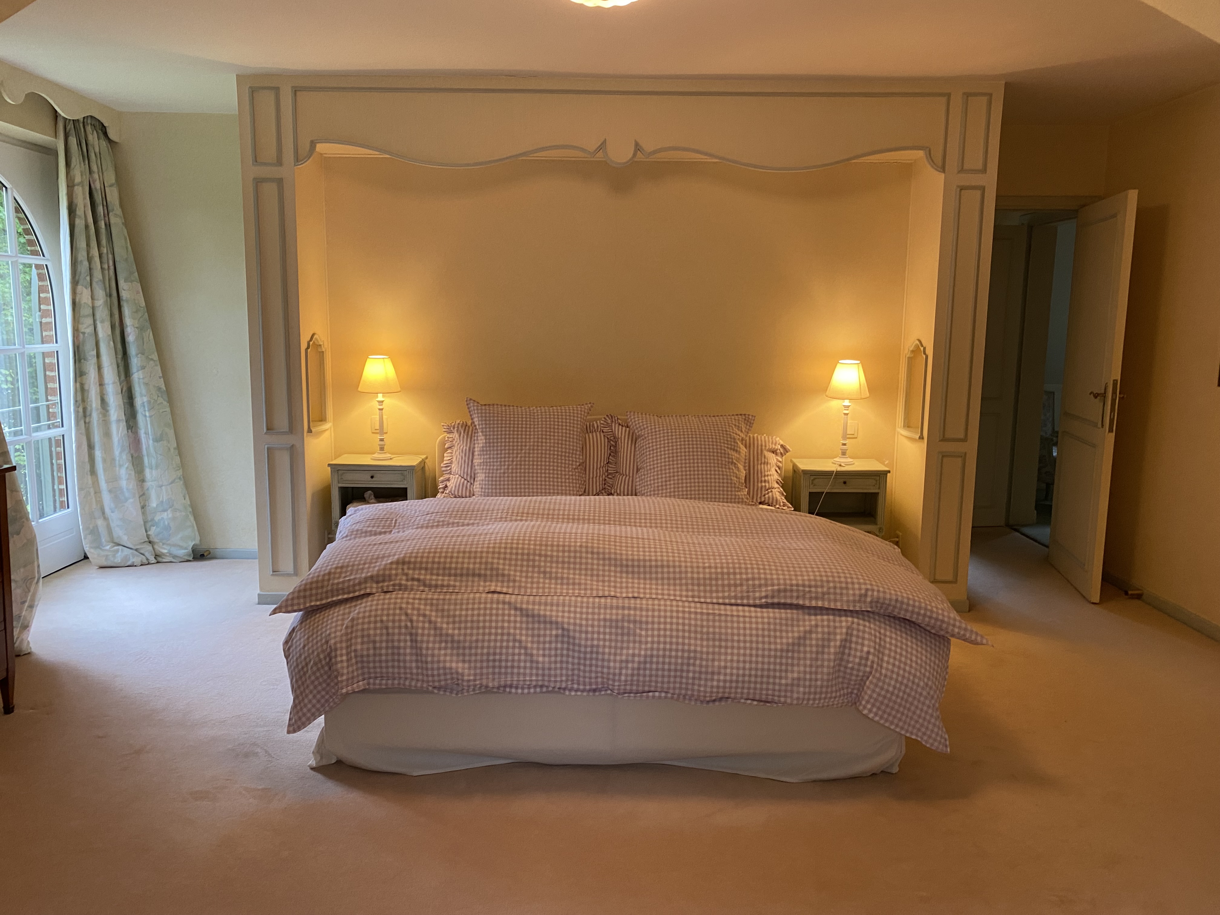 Chambre avec grand lit double niché dans une alcôve et lampes de chevet