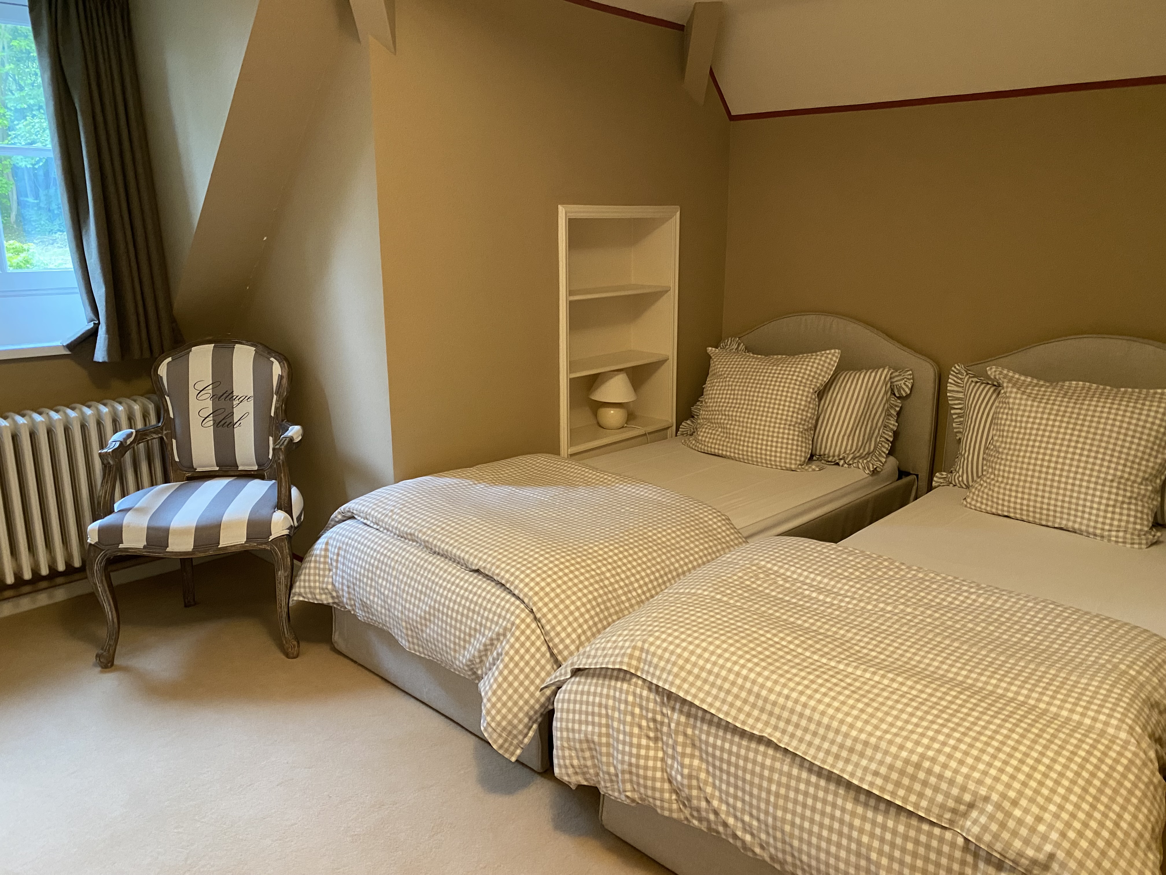 Chambre avec deux lits jumeaux à carreaux et fauteuil Cottage Club