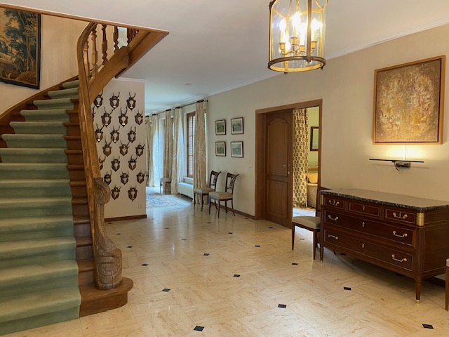 Hall d'entrée avec escalier en bois, sol en pierre et trophées de chasse
