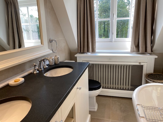 Salle de bain avec double vasque, baignoire et carrelage beige