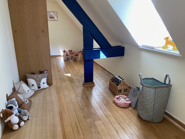 Espace de jeux avec peluches, château fort et poutre bleue apparente