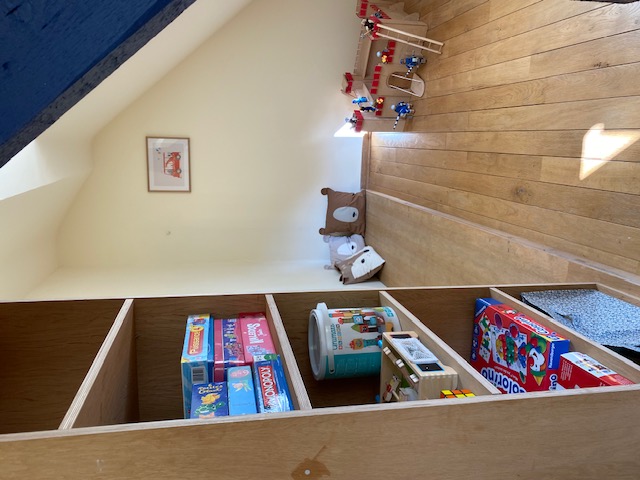 Coin jeux avec jeux de société, château en bois et coussins animaux