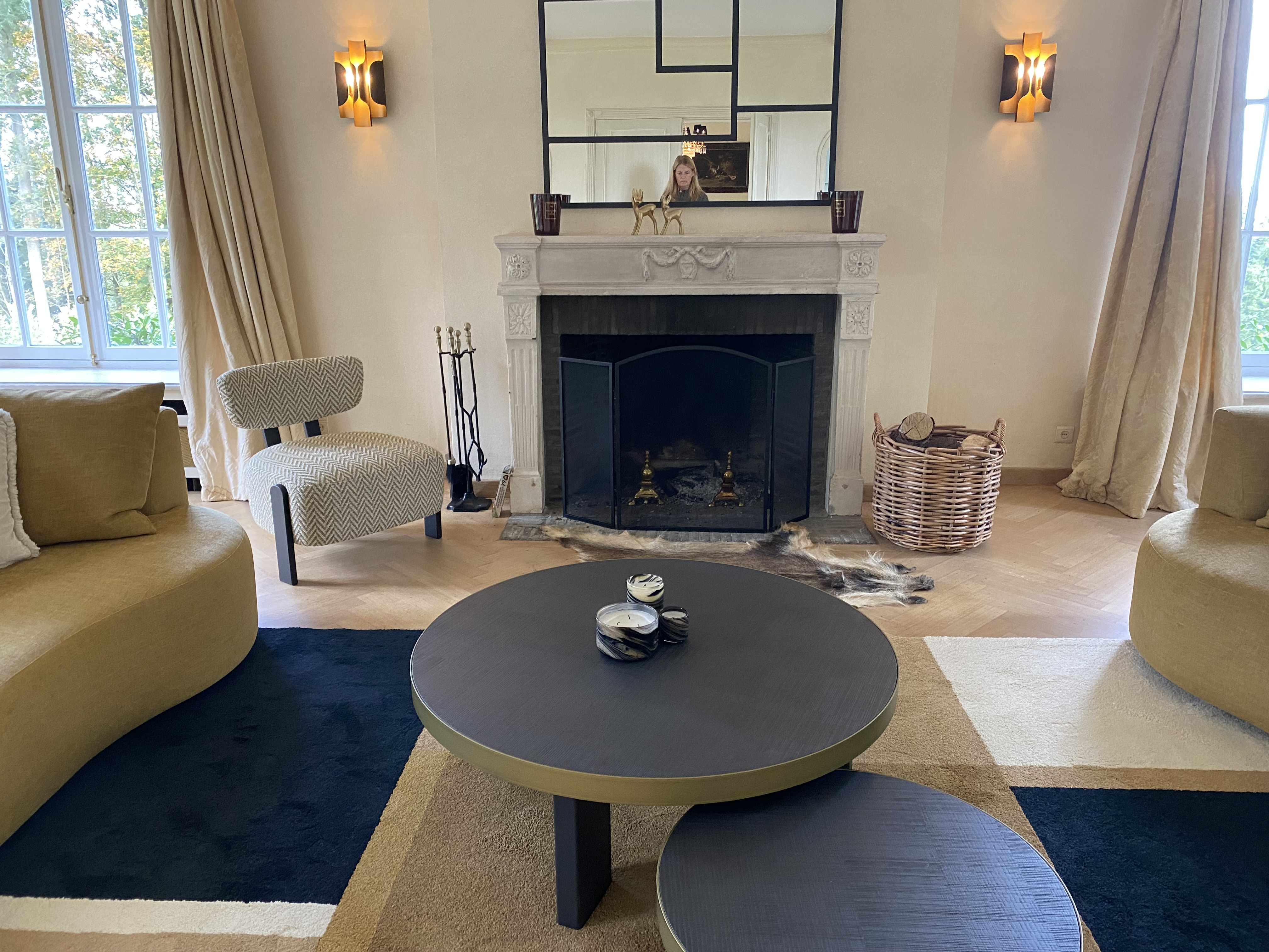 Cheminée en pierre avec canapés arrondis, tables basses rondes et tapis moderne