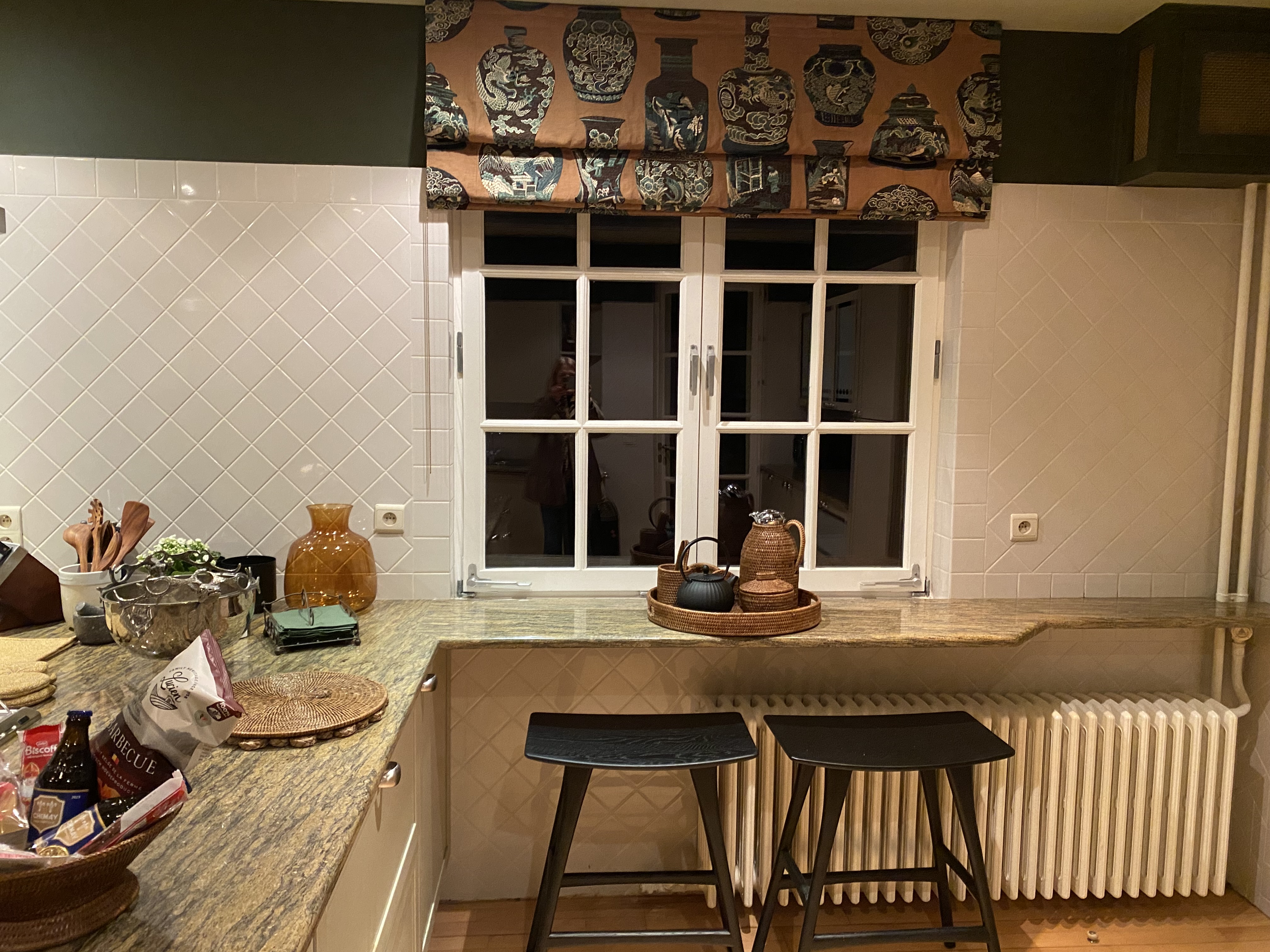Coin cuisine avec comptoir en granit, tabourets noirs et fenêtre décorative